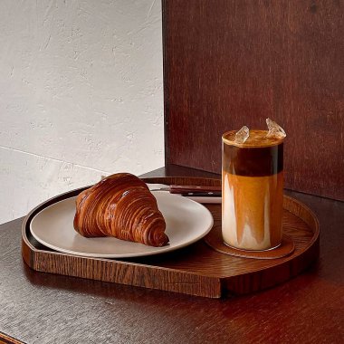 Bir bardak taze kruvasan çikolata ve ahşap masada kahve.