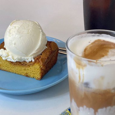 Bir fincan kapuçino, bir kek ve bir fincan kahve.