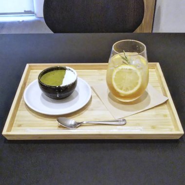 Bir fincan yeşil çay, bir kaşık ve tahtanın üzerinde bir kaşık.