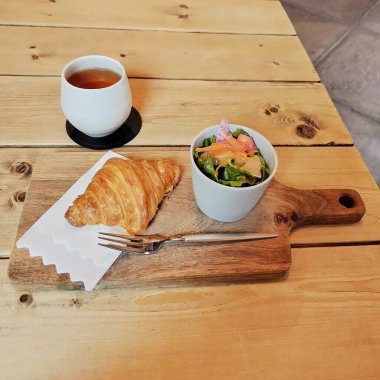 Tahta zemin üzerinde kahve ve çay olan taze kruvasan.