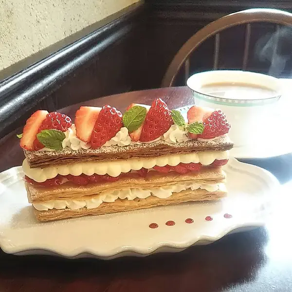 Üzerine krem şanti ve çilek dökülmüş lezzetli pasta dikey görünümü.