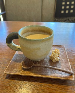 Bir fincan çay ve bir kupa sıcak içecek tahtadan bir masada.