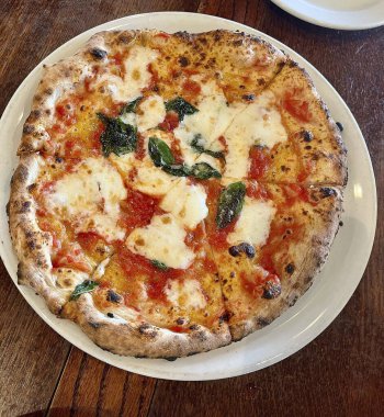 Tabakta domates peynirli ve mantarlı pizza.