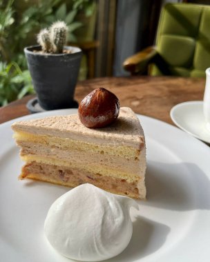 Bir fincan kahveyle beyaz tabakta bir parça kek.