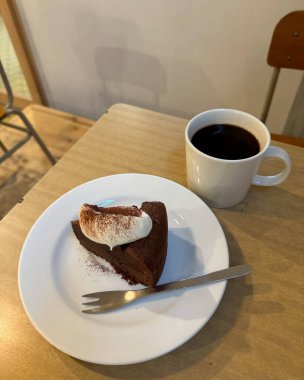 Bir fincan kahve ve beyaz ahşap arka planda bir kek.