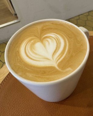 Bir fincan kahve ve beyaz arka planda bir kalp latte..