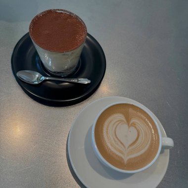 Kafedeki ahşap masada kapuçinolu bir fincan sıcak kahve.