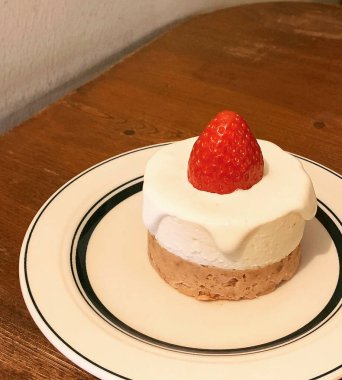 Beyaz bir tabakta çilekli ve kremalı ev yapımı lezzetli bir pastanın yakın çekimi.