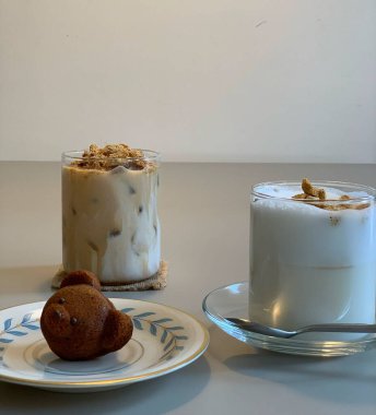 Bir fincan kahve, bir bardak süt ve masanın üzerindeki kekin dikey yakın çekimi.