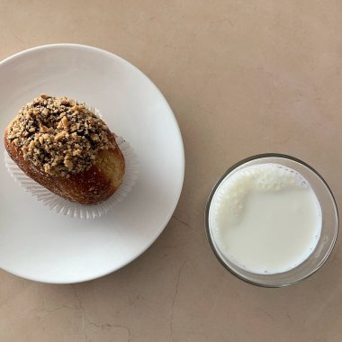 Beyaz bir fincan beyaz bir tabak ve çikolatalı bir kaşık ve beyaz bir tabakta bir süt.