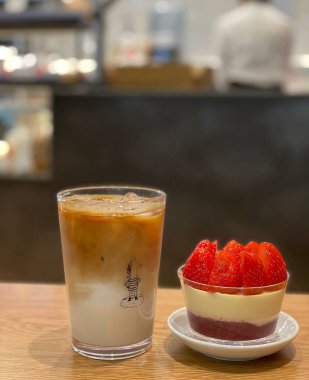 Masanın üzerinde çilekli kek ve kahve var.