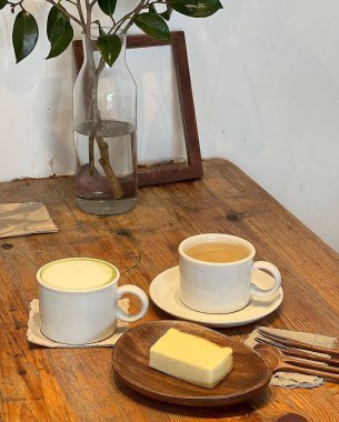 Bir fincan çay, bir kaşık ve bir fincan kahve, ahşap bir masada.