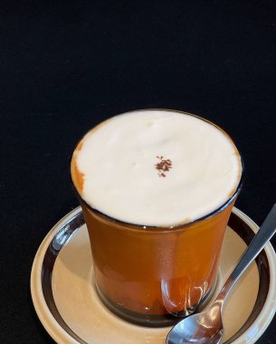 Siyah arka planda bir fincan latte.