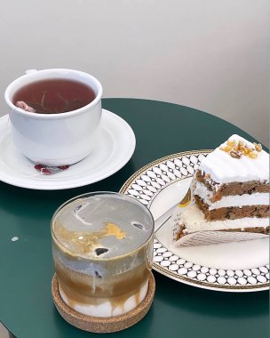 Bir fincan çayla birlikte bir kekin dikey görüntüsü.