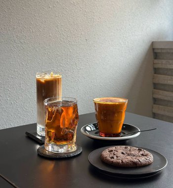 Beyaz arka planda bir bardak sade kahveyle beyaz fincanda kahve ve kurabiye..