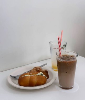 Sütlü buzlu kahve ve beyaz masada ekmek.