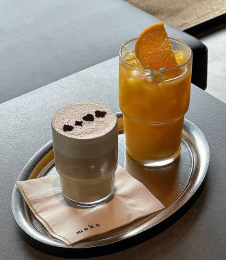 Kahve ve kapuçino bir bardakta, latte ile ahşap masada.