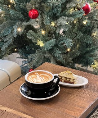 Bir fincan kapuçino ve ahşap masa üzerinde latte sanatı.