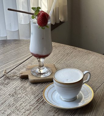 Krem şantili ve çilekli bir fincan sıcak içecek.