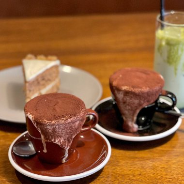 Bir bardak kahve, bir fincan kahve ve ahşap bir masada kaşık.