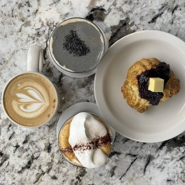 Bir fincan kahve ve bir parça çikolatalı kalp şeklinde bir pasta.