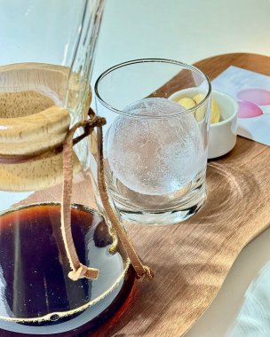 Bir bardak su, bir fincan kahve ve ahşap bir masada bir pipet.