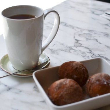 Bir fincan çay, lezzetli çörekler ve siyah bir çay tabağı.