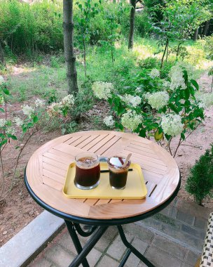 Tahta bir masada bir fincan kahve ve çiçekler.