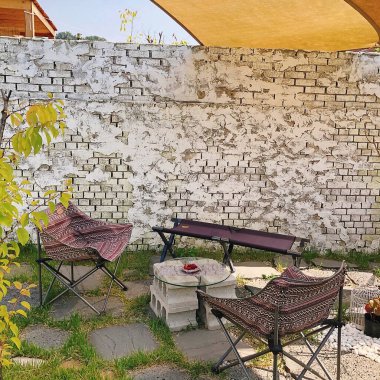 Masadaki tuğla duvarın yanında duran güzel, beyaz, siyah ve sarı çiçeklerin dikey görüntüsü.