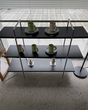 Ahşap masalı kahve dükkanı, kahve makinesi ve camlı raflar.