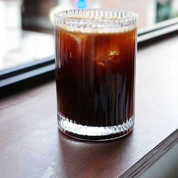 Ahşap masada buzlu bir bardak buzlu kahve.