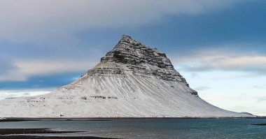 Güneşli bir günde beyaz bulutlu güzel mavi bir gökyüzü olan Vvik dağının dikey görüntüsü.