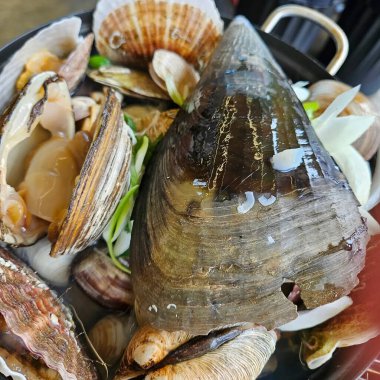 Siyah bir tabakta deniz ürünleri ve midyeler.