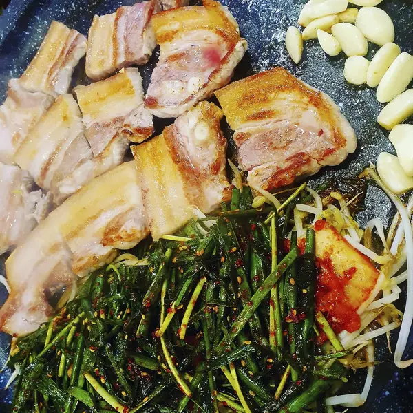 Baharatlı domuz göbeği ve siyah tabakta otlar. Üst görünüm, kapat - kapat