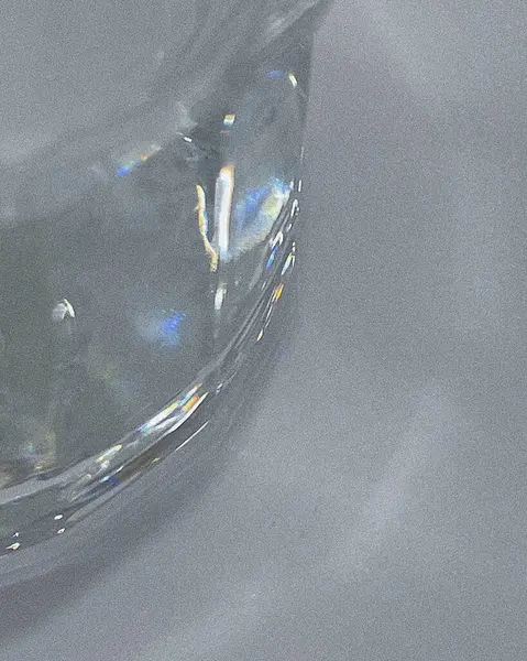 Gri zemin üzerinde beyaz bir damla su bulunan cam şeffaf su, yakın çekim. soyut arkaplan