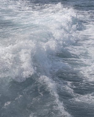 Deniz dalgaları güneşli havada sahile vuruyor.