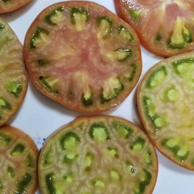 Dilimlenmiş kırmızı domatesler beyaz tabakta.