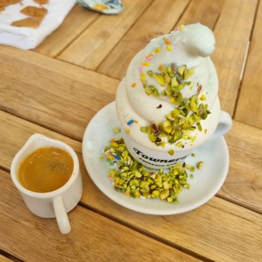 Bir fincan latte kahve, marşmelov ve ahşap masada krema.