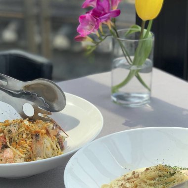 Masada çatal ve beyaz tabakla lezzetli bir makarnanın dikey görüntüsü.