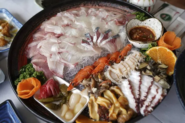 Deniz ürünleri, taze balık, karides ve diğer yemekler masada..