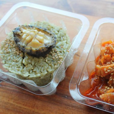 Plastik kabın içinde tavuk ve sebzeli pilav.