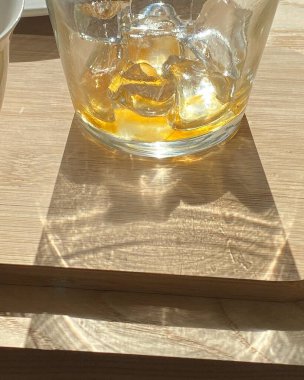 Tahta masada buz küpleri olan bir bardak viski.