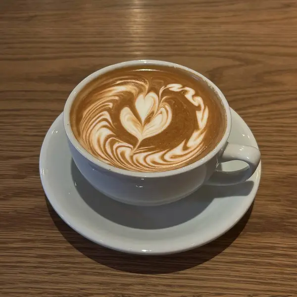 Tahta arka planda kalbi olan sıcak bir kahve..