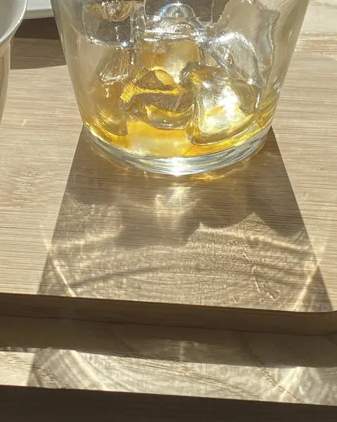 Tahta masada buz küpleri olan bir bardak viski.