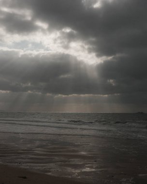 Arka planda bulutlarla denizin üzerinde gün batımı