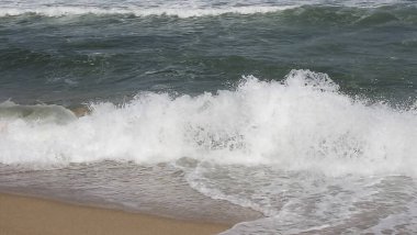 Kumsalda deniz dalgaları ve köpük