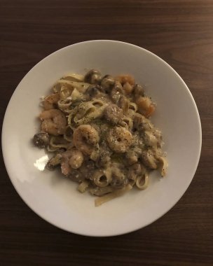 Beyaz tabakta deniz ürünleri ve karidesli spagetti.