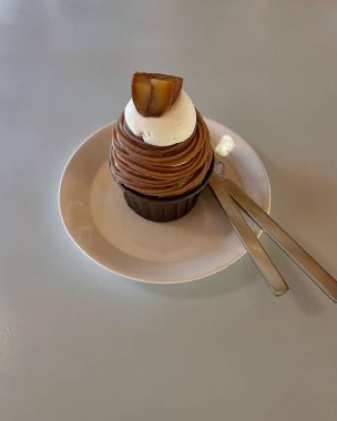 Bıçaklı bir parça pasta ve gri bir arka planda tahta bir tabakta çatal.