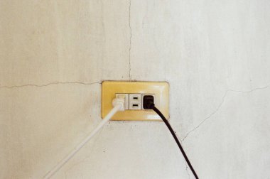 Beyaz duvarda kabloları olan elektrik prizi.