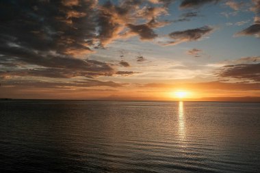 Gölde gün batımı, denizin üzerinde güneş, bulutlar ve güneş.